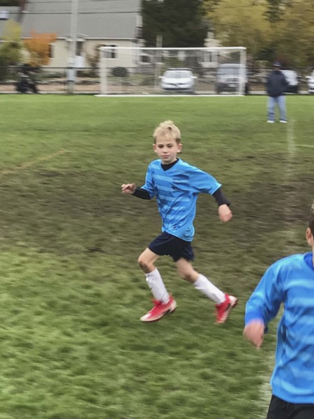 Young boy in soccer uniform running on soccer field