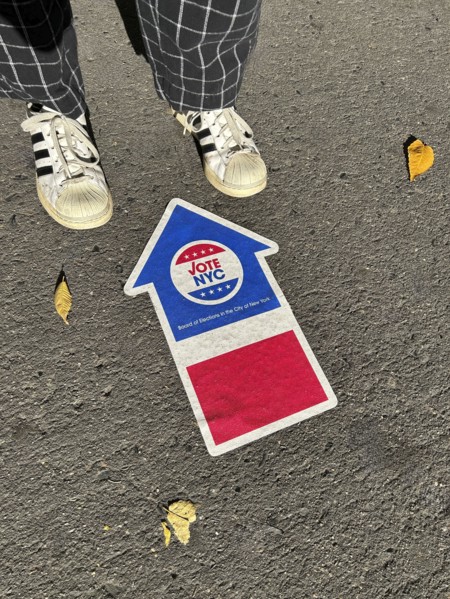 High angle view of person standing near NYC board of elections early voting arrow sign adhered to