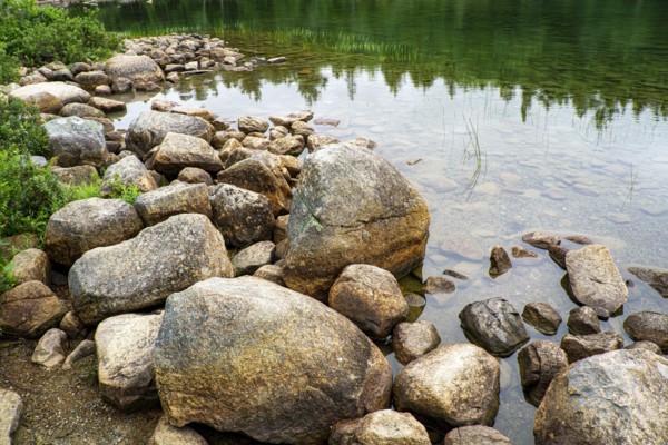 Large rocks at edge of clear lake, Acadia National Park, Maine, USA
