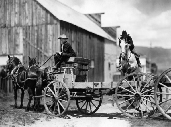 Fred Thomson (jumping over wagon on horse), on-set of the silent western film, "Jesse James",
