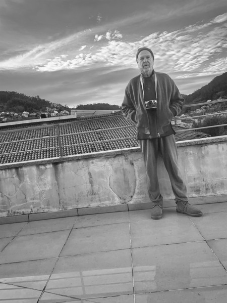 Full-length portrait of mature adult man standing on bridge overlooking rooftops, Bueu, Spain