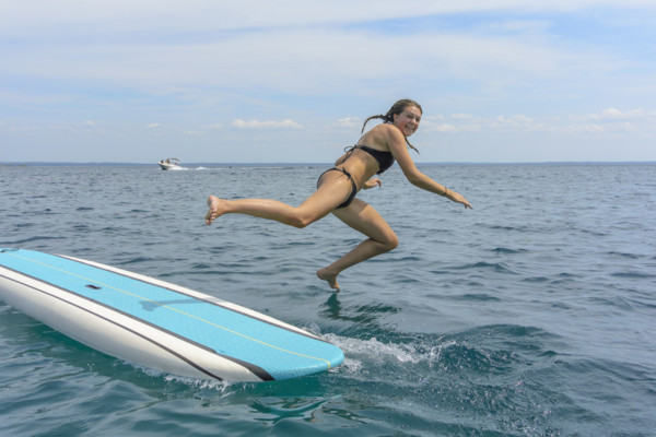 Young adult woman jumping off paddle board