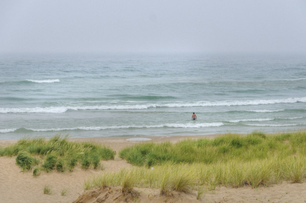 Rear view of swimmer wading into lake on cloudy day
