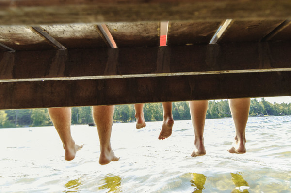 Family with dangling feet sitting on dock