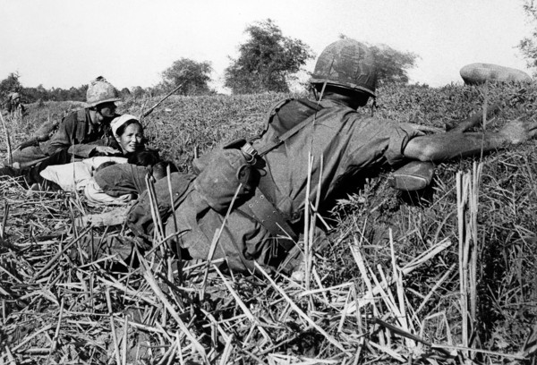 American soldier of 1st Infantry Division motioning to woman refugee to keep her children's heads