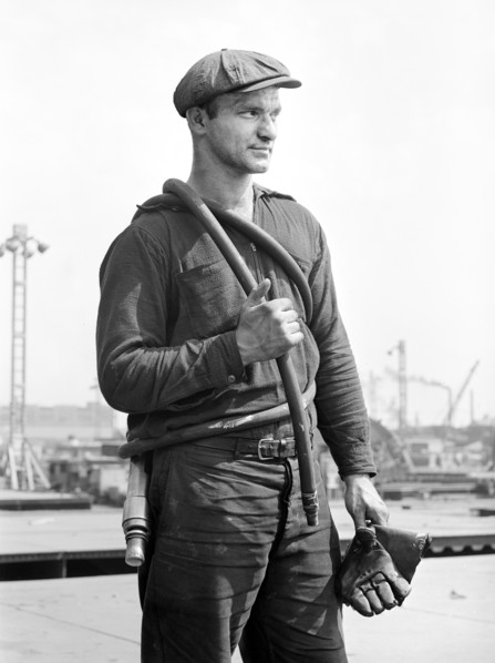 Factory worker carrying rubber hose, Bethlehem-Fairfield shipyards, Baltimore, Maryland, USA,