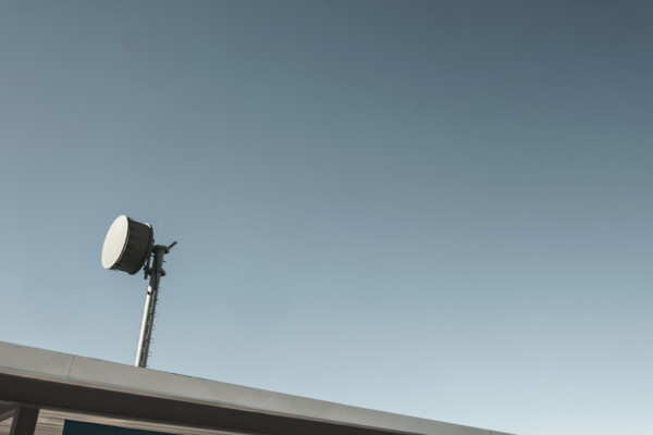 Microwave transmitter mounted to the roof against blue sky