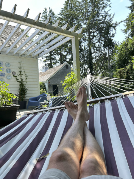 View of mid-adult man's bare legs and feet while relaxing in hammock on summer day