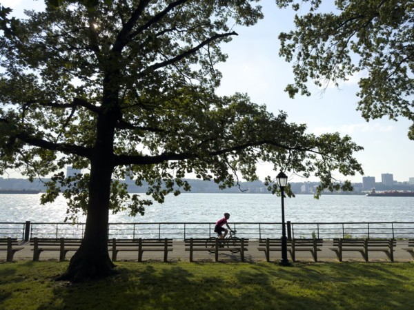 Bicyclist on westside bike path along Hudson River with view of New Jersey in background, Manhattan, New York City