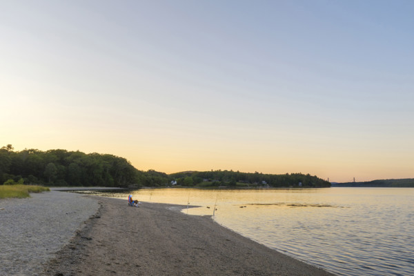 Two people fishing at beach at sunset