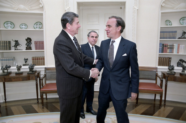 U.S. President Ronald Reagan shaking hands, with Rupert Murdoch as Director of U.S. Information