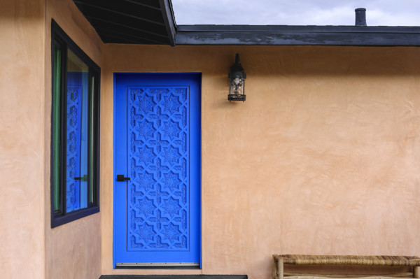 Blue carved wood door on stucco house