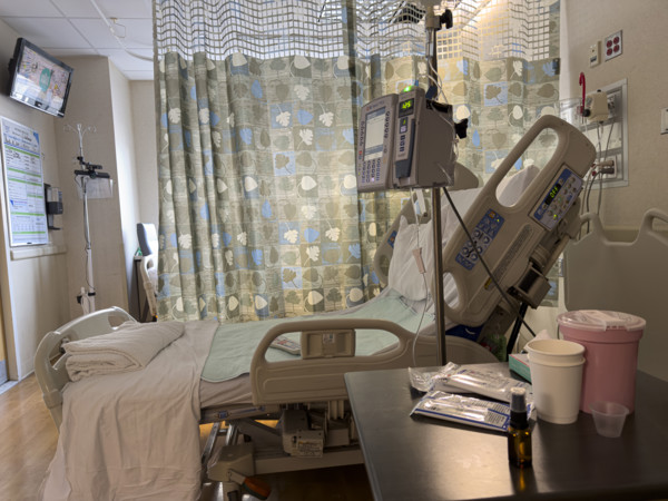 Empty hospital bed in patient room with medical equipment