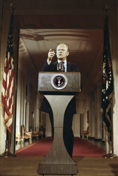 U.S. President Gerald R. Ford standing at lectern during first press conference, White House East