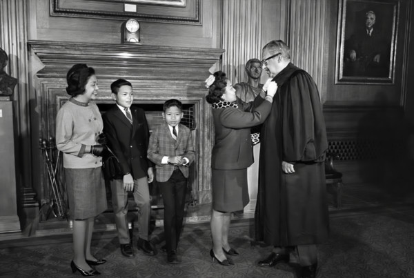 Thurgood Marshall, Associate Justice of the U.S. Supreme Court, assisted with his robes by his wife