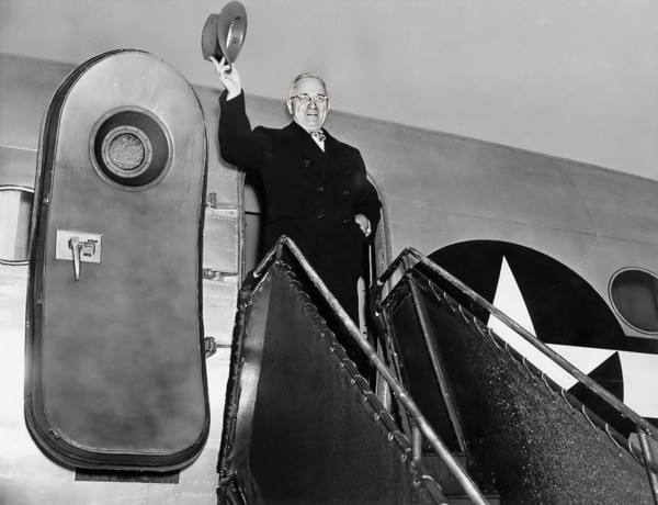 President Harry S. Truman waving his hat from door of his airplane, "Sacred Cow" as he prepares to