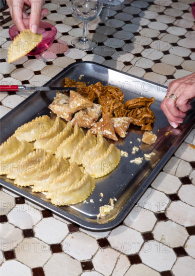 Woman's hands reaching toward tray filled with traditional pastries