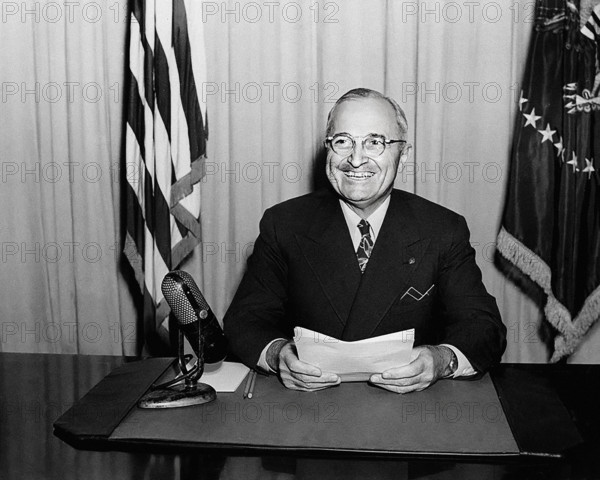 U.S. President Harry S. Truman smiling for photographers while delivering radio speech to the