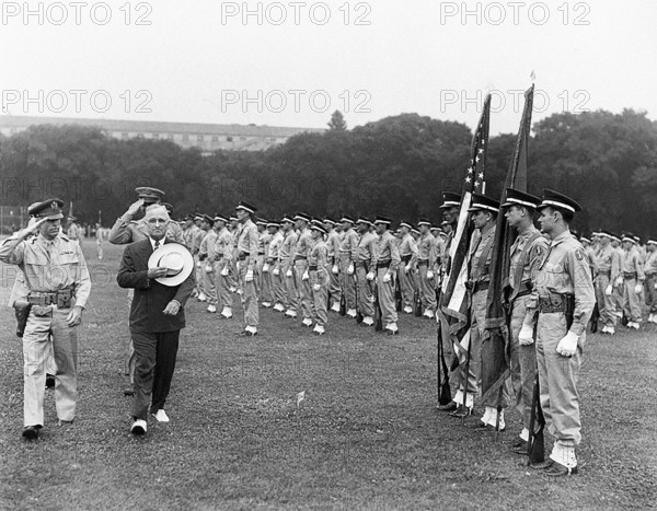 U.S. President Harry S. Truman (in civilian suit and hat) and military officers saluting as they