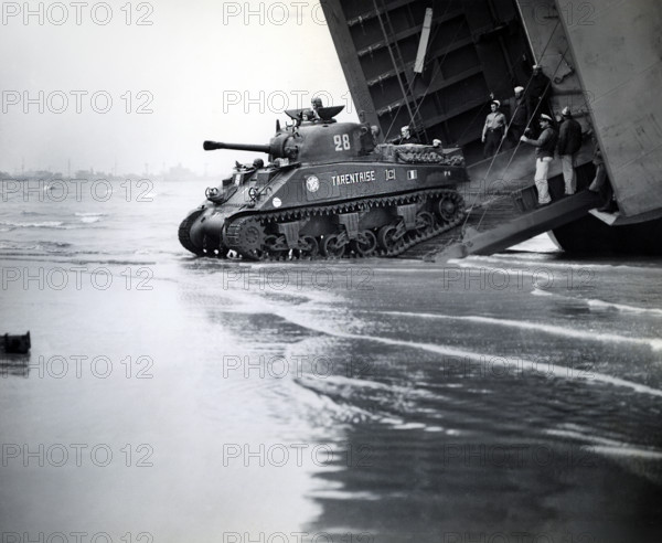 Sherman tanks, manned by French armored troops, rolling down landing ship ramp onto Utah beach,