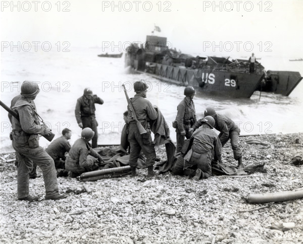 American soldiers applying artificial respiration on two other soldiers who reached the north coast
