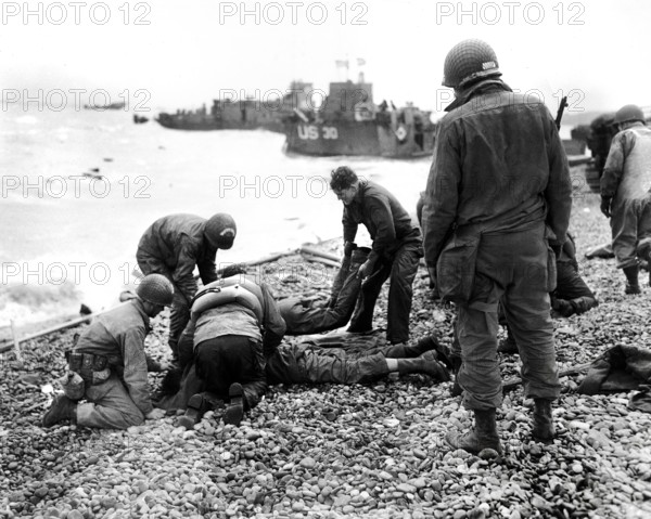 American soldiers applying artificial respiration on two other soldiers who reached the north coast