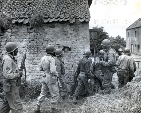 Platoon of Negro troops surrounding farmhouse as they prepare to eliminate a German sniper holding