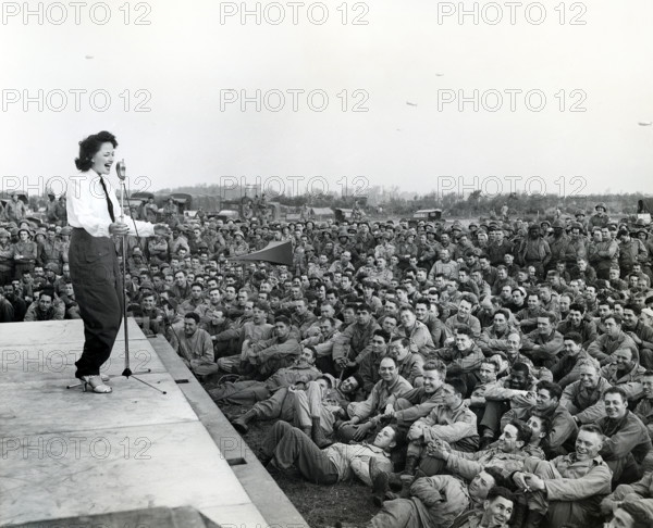 Crowd of GIs flock around an improvised platform to witness first U.S.O. camp show, France, U.S.