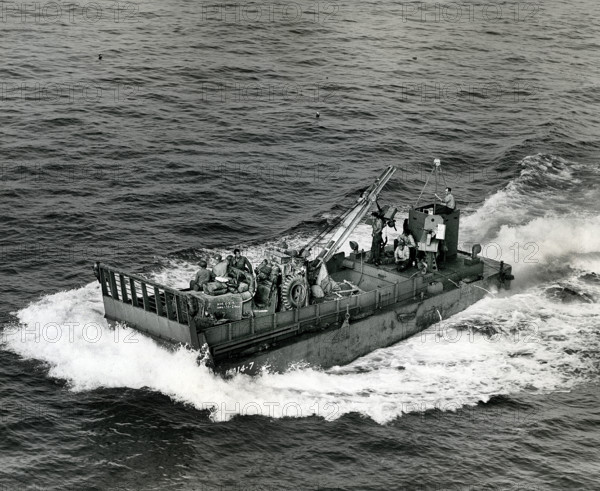Small landing boat transporting artillery and machinery back and forth between ships and beachhead,