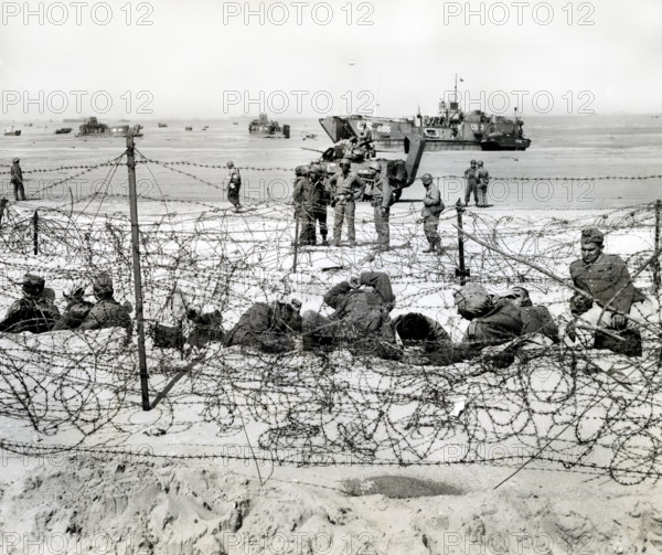 German prisoners resting in barb-wired enclosure after being interrogated by American soldiers,
