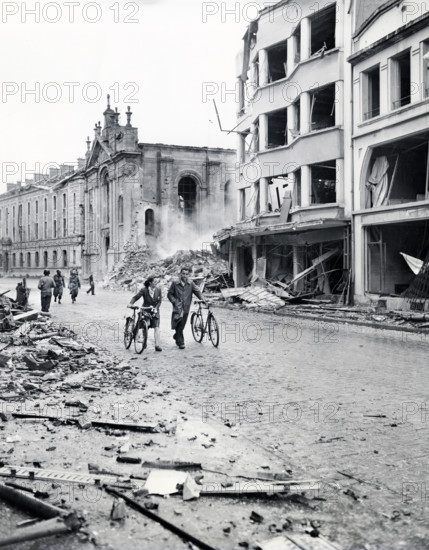 Residents move past bombed buildings hit by German Luftwaffe in an attempt to destroy bridge over
