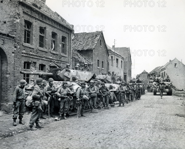 Infantrymen of 1st Division, U.S. First Army, resting beside military tanks, Monchengladbach, North