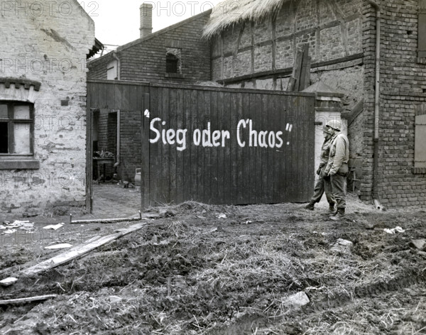 Two members of 1st Engineer Battalion, 16th regiment, 1st Division, U.S. First Army, reading sign