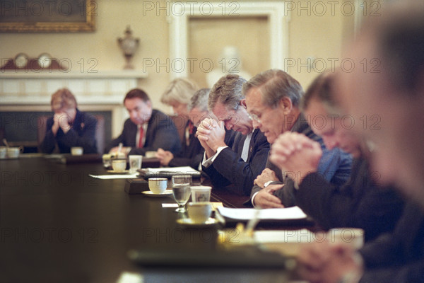 U.S. President George W. Bush bowing his head as U.S. Secretary of Defense Donald Rumsfeld leads