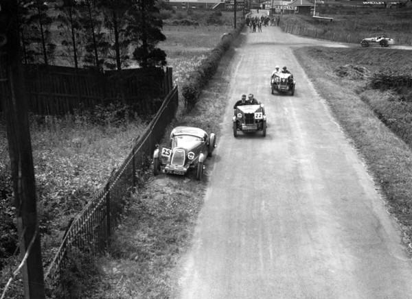 Two MG M types passing a broken down 1928 Alta Prototype, JCC Members Day, Brooklands, 4 July 1931. Artist: Bill Brunell.