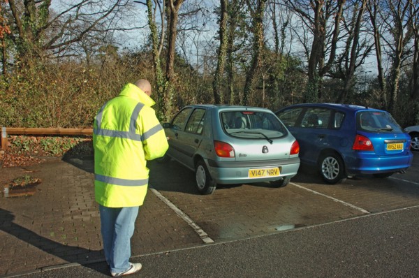 Car Park attendant recording car registration numbers. Artist: Unknown.