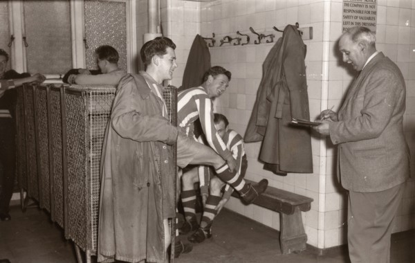 Footballers adjust their boots in the locker room, 1953. Artist: Unknown