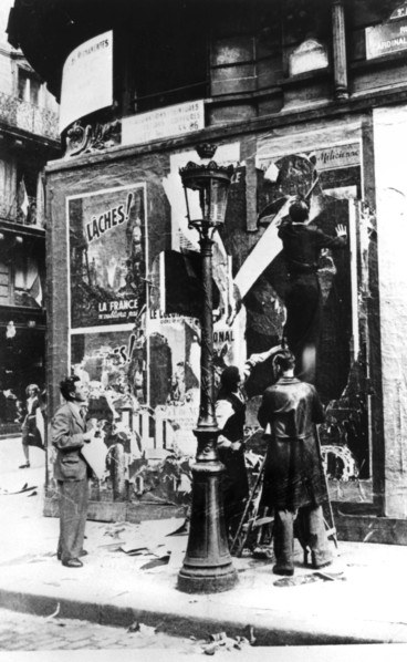 Billboard with men putting up propaganda posters, Paris, World War II, 1939-1945. Artist: Unknown