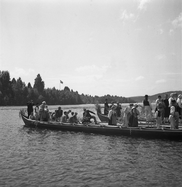 People arrive in long boats, called church boats, for the Midsummer celebrations, Sweden, 1941. Artist: Torkel Lindeberg