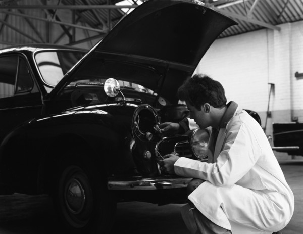 Auto electrician changing a light bulb on a Morris Minor, Nottingham, Nottinghamshire, 1961.  Artist: Michael Walters