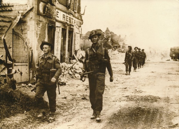 British troops walk through the village of Douet, after the fall of Bayeux, June 1944. Artist: Unknown