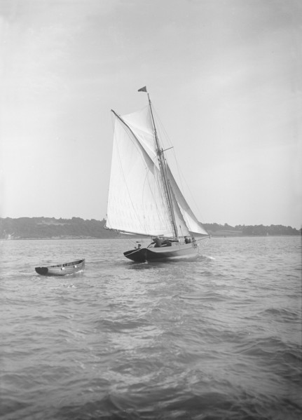 The cutter 'Citara' under sail and towing tender, 1911. Creator: Kirk & Sons of Cowes.
