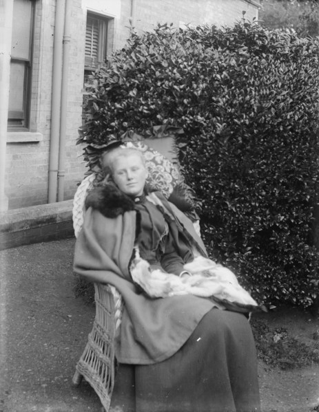 Woman sitting in a chair in a garden, c1900. Creator: Kirk & Sons of Cowes.