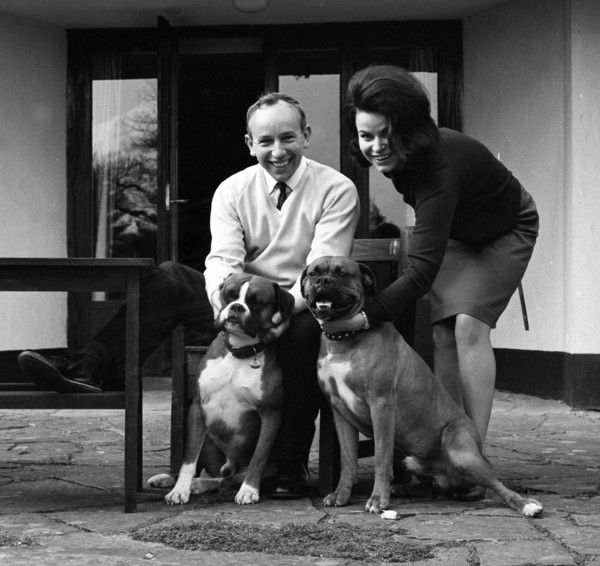 John Surtees relaxes at home with his wife and pet dogs in 1966. Creator: Unknown.
