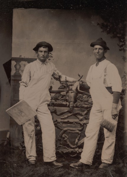 Two Plasterers in Overalls Leaning on a Rustic Fence, 1870s-80s.