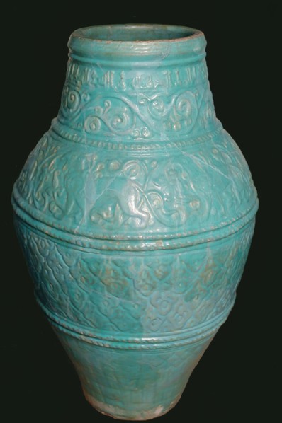 Large Turquoise Jar, Iran, 12th-13th century. Motifs typical of the Seljuq period including winged griffins and arabesque design. with inscriptions of good wishes  in small kufic script.