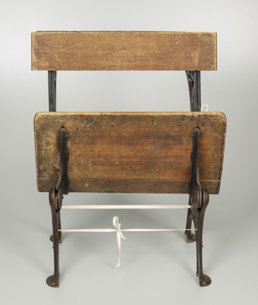 Wood and iron school desk with a foldable seat.
