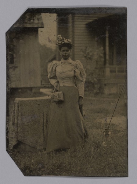 Tintype of a woman wearing a dress with hat and bag, 1890s. Creator: Unknown.