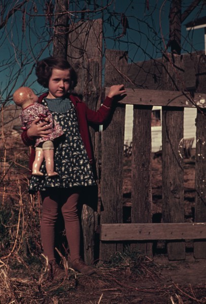 Girl with doll standing by fence, between 1941 and 1942. Creator: Unknown.