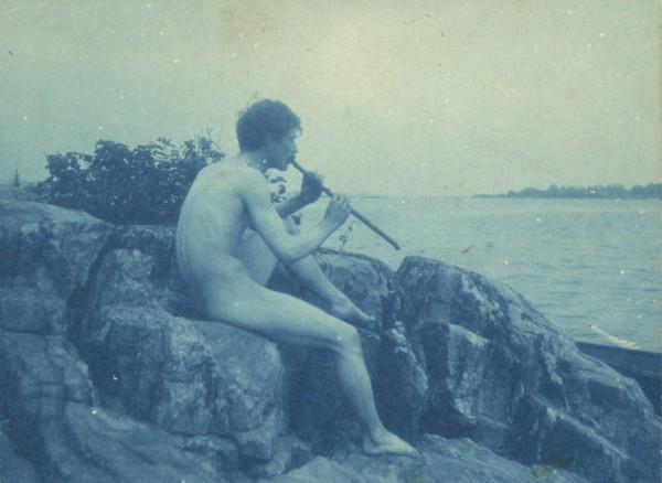 Man posed on rocks, nude, playing pipe (Pan), between 1885 and 1900.